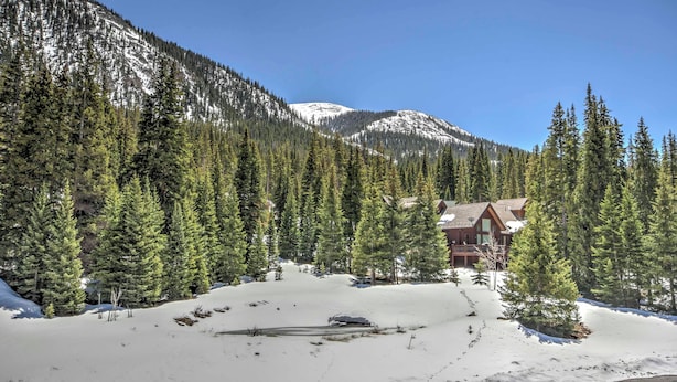 Eine Lodge, umgeben von schneebedeckten Bergen und dichten immergrünen Bäumen.