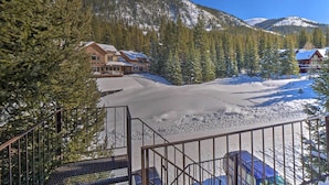 Eine Lodge mit verschneitem Zufahrtsweg, umgeben von immergrünen Bäumen und Bergen.