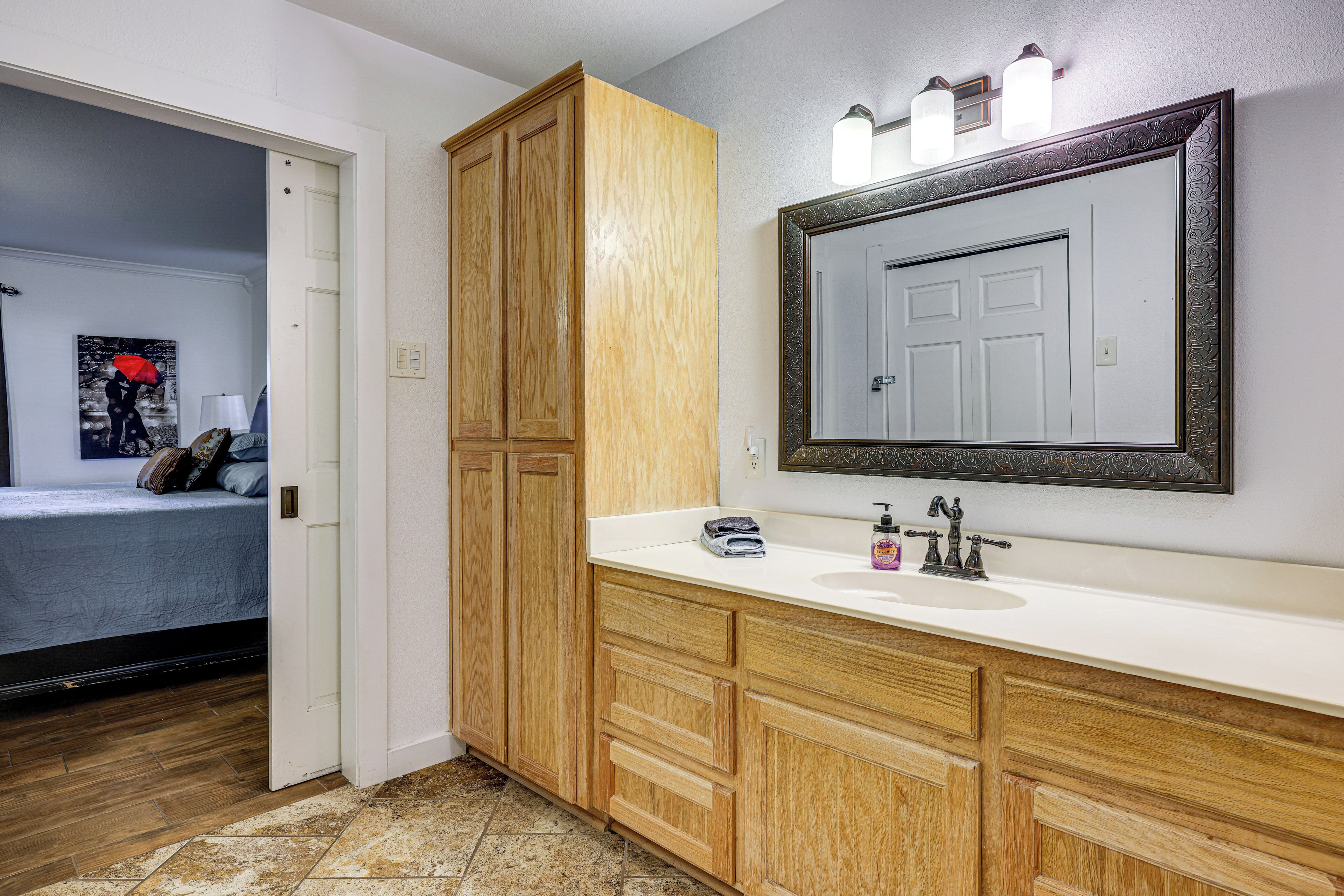 A bathroom with wooden cabinets, a white sink, and a large mirror.