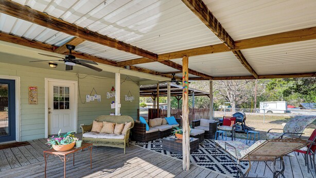 A covered porch with wicker furniture, a ceiling fan, and a wooden table with a flower pot. - Charming Lake Retreat w/ Patio & Boat Parking! (Canyon Lake)