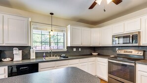 A modern kitchen with white cabinets, a granite countertop, a stainless steel oven, and a microwave. - Charming Lake Retreat w/ Patio & Boat Parking! (Canyon Lake)