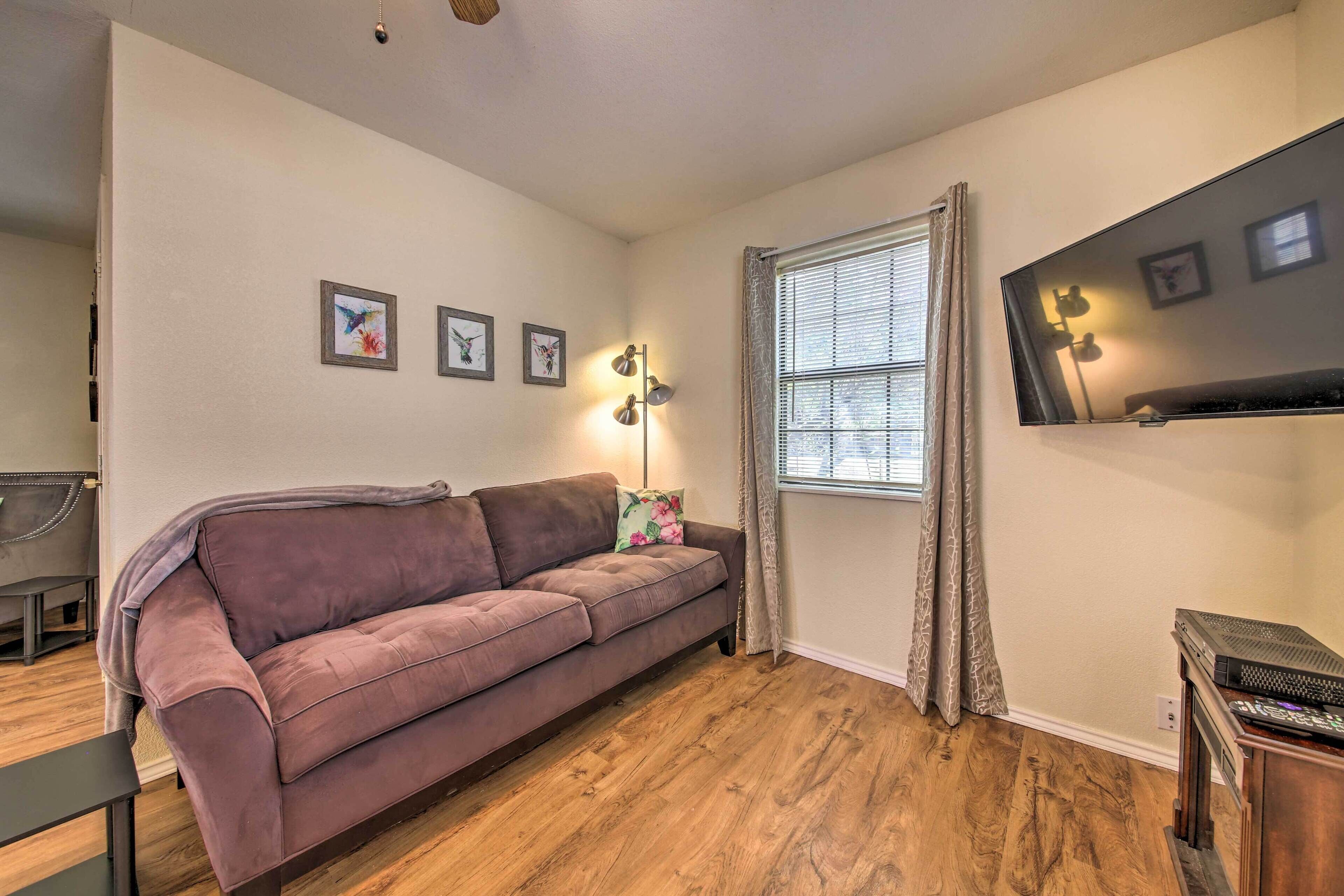 A living room with a sofa, a lamp, a TV, and a window with curtains.