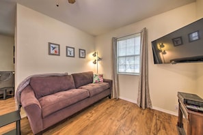 A living room with a sofa, a lamp, a TV, and a window with curtains.