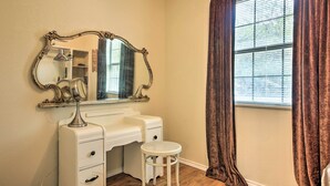 A room with a vanity, a mirror, a stool, and a window with curtains. - Cozy Canyon Lake Cottage: 1 Mi to Guadalupe River! (Canyon Lake)