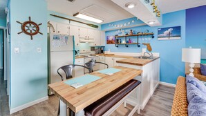 A compact kitchen with white cabinets, a wooden countertop, and a dining area with a bench. - PCB Apt w/ Balcony & Gulf Views: Walk to Beach (Panama City Beach)