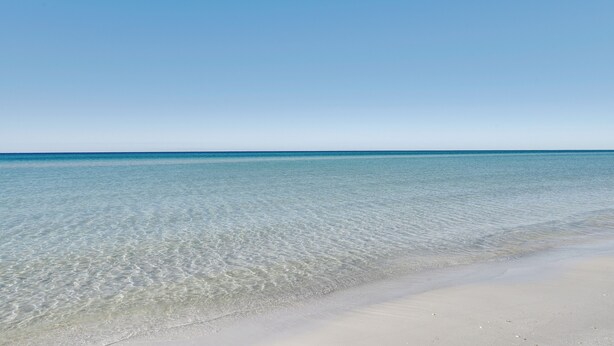 A clear beach with calm water and a sandy shore. - PCB Apt w/ Balcony & Gulf Views: Walk to Beach (Panama City Beach)