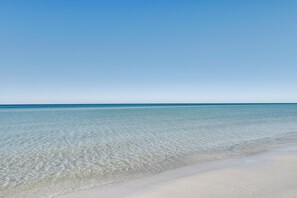 Ein sauberer Strand mit ruhigem Wasser und einem sandigen Ufer.