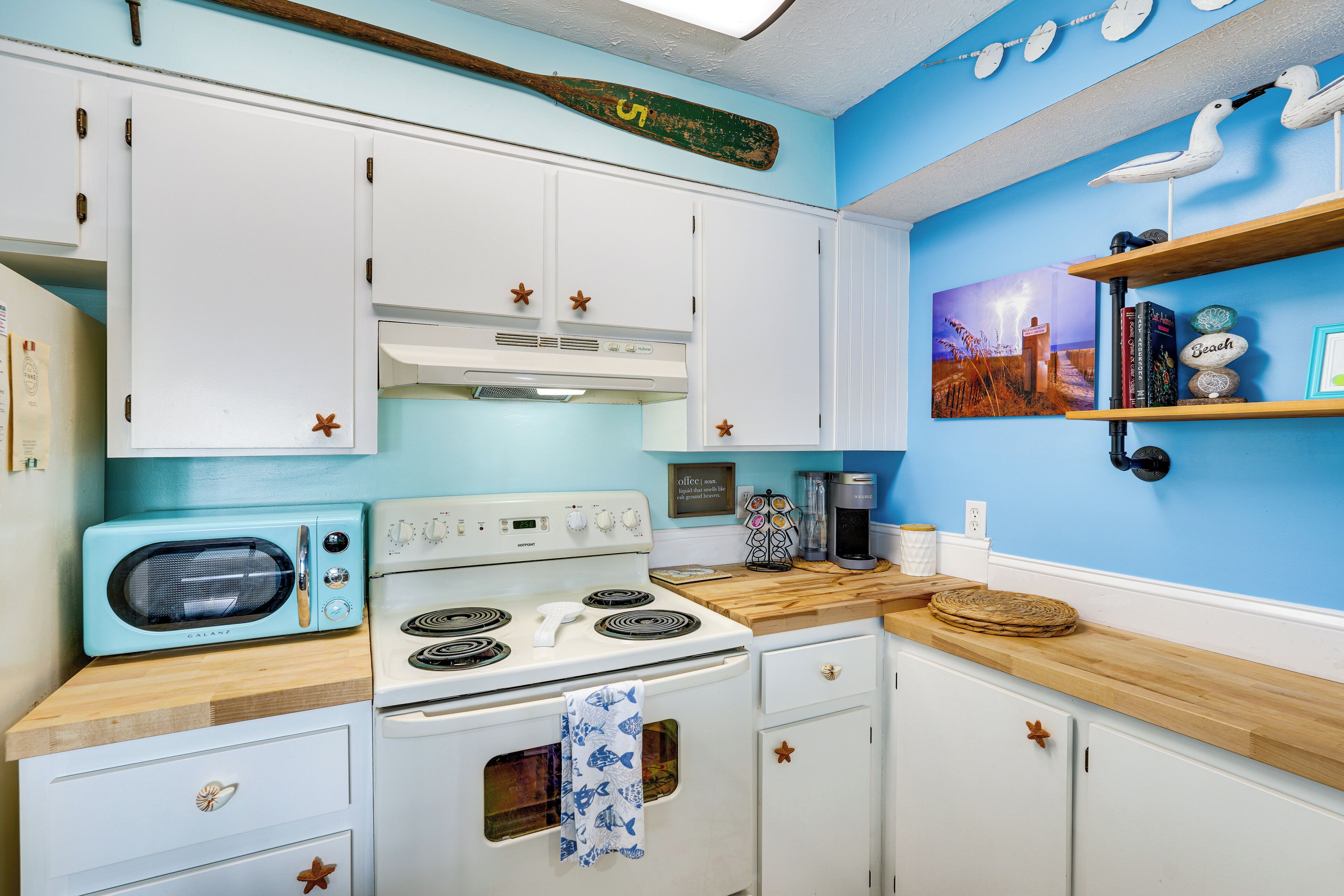 Une cuisine avec des armoires blanches, une cuisinière, un four à micro-ondes et un plan de travail en bois.