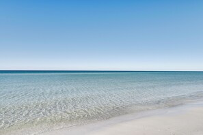 Ein freier Blick auf einen Strand mit ruhigem Wasser und sandigem Ufer.