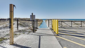 A pathway leading to a beach with a wooden post and a metal gate. - PCB Studio w/ Private Patio: Steps to Beach! (Panama City Beach)