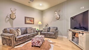 A living room with two leather sofas, a cowhide rug, and mounted deer heads on the walls. - Lakeview Escape w/ Hot Tub, 1 Mi to Canyon Lake (Canyon Lake)