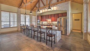 A spacious kitchen with a large island, wooden beams, and a stone accent wall. - Lakeview Escape w/ Hot Tub, 1 Mi to Canyon Lake (Canyon Lake)