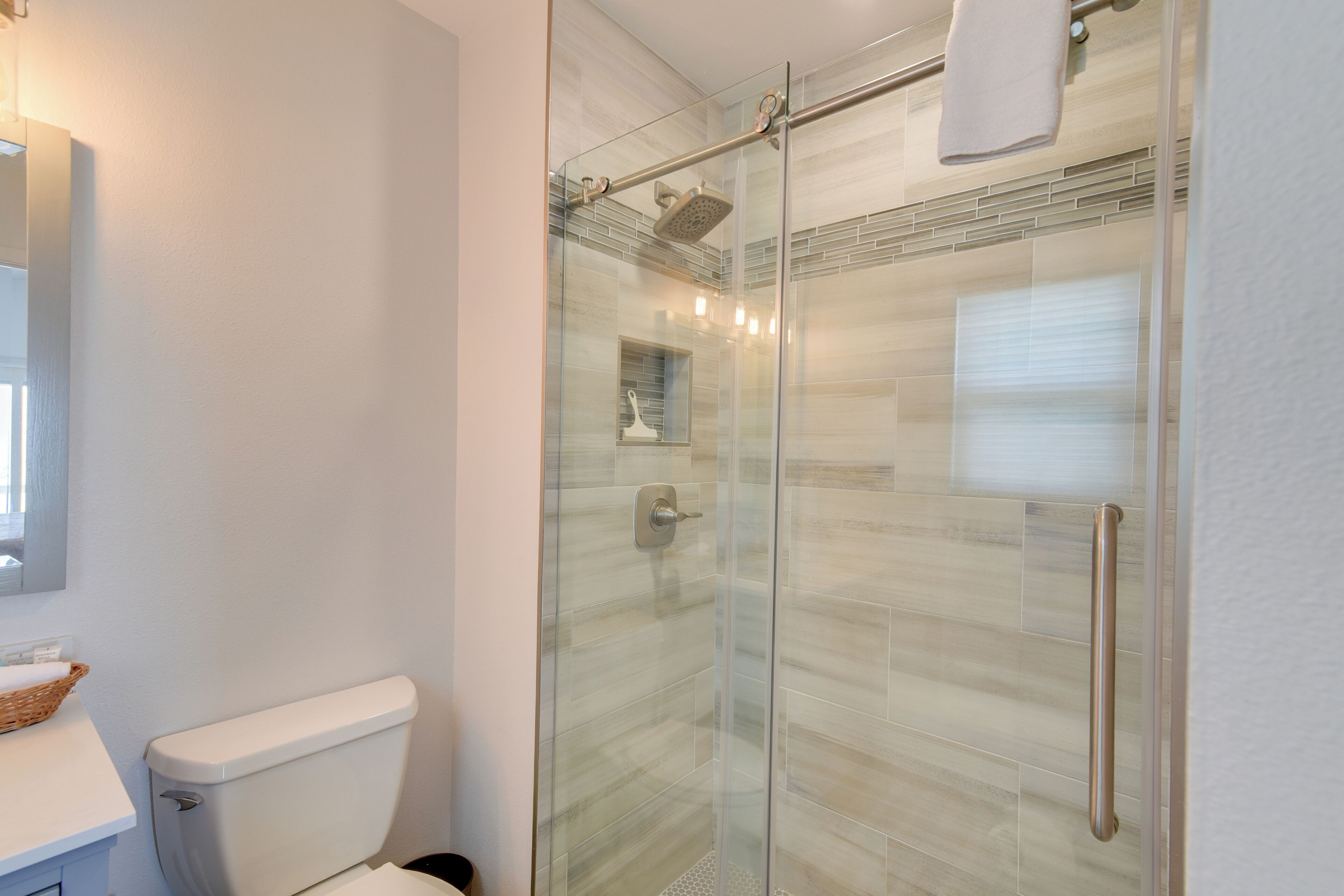 Un baño moderno con ducha de vidrio, inodoro blanco y toallero visible.