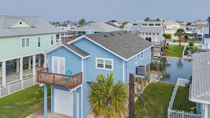 A residential area with houses, a small waterway, and a balcony with chairs.