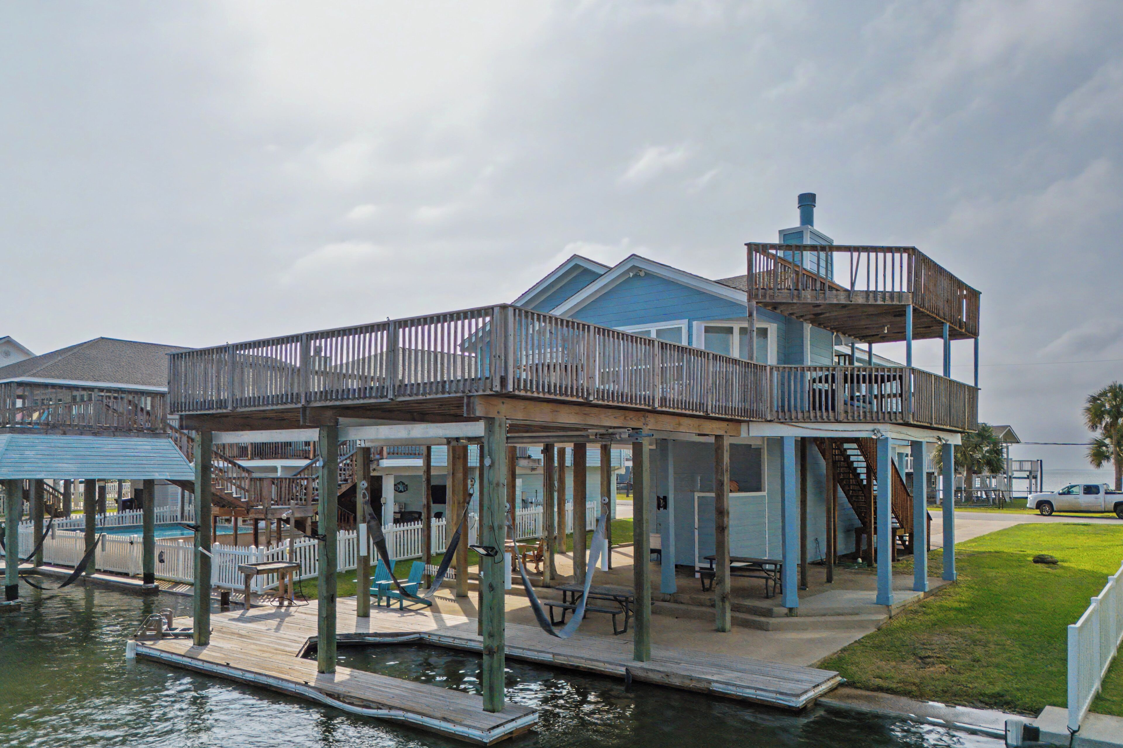A waterfront house with a dock, outdoor seating, and a covered deck area.