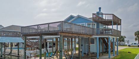 A waterfront house with a dock, outdoor seating, and a covered deck area.
