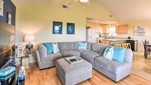 A modern living room with a sectional sofa, ottoman, and a ceiling fan. - Walk to Sea Isle Beach: Bright Galveston Home! (Galveston)