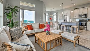 A spacious living area with a sofa, coffee table, and a view of the kitchen and dining area. - Villa Azul Galveston Home: Modern & Beachfront! (Galveston)