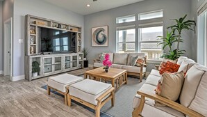A spacious living room with a television, comfortable seating, and a ceiling fan. - Villa Azul Galveston Home: Modern & Beachfront! (Galveston)
