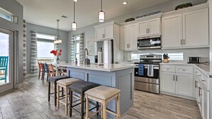 A modern kitchen with white cabinets, stainless steel appliances, and a large island with bar stools. - Villa Azul Galveston Home: Modern & Beachfront! (Galveston)