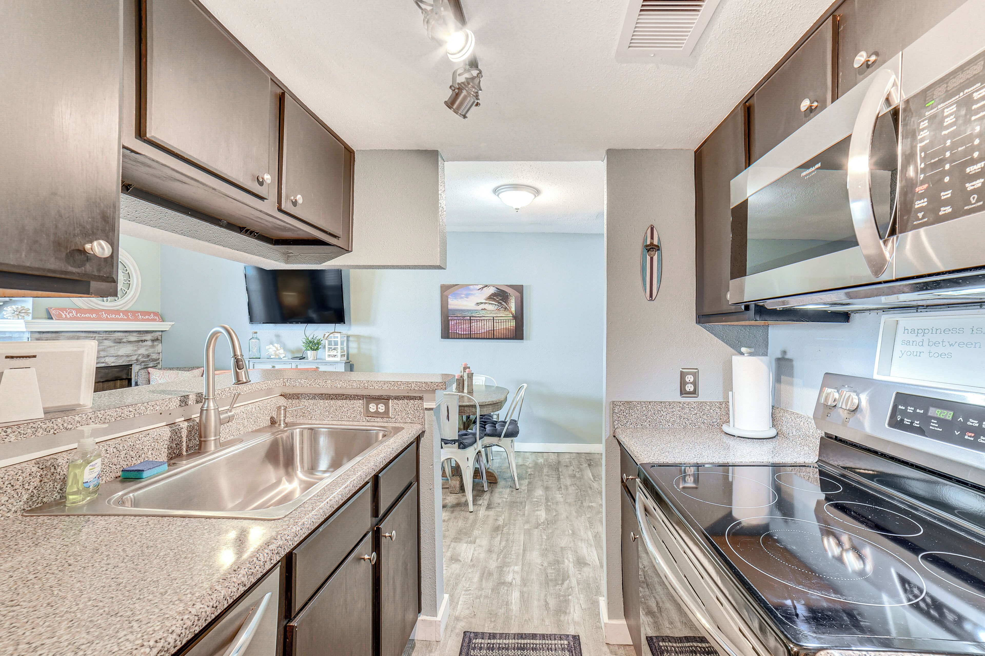 A modern kitchen with stainless steel appliances, a granite countertop, and a dining area with a table and chairs.