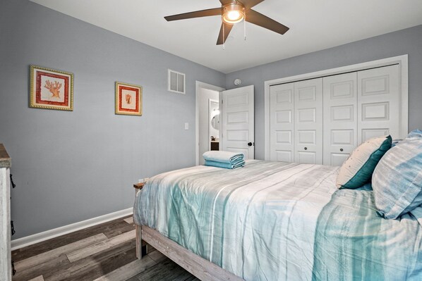 A bedroom with a bed, a ceiling fan, and a white door.