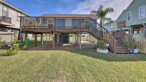 A residential property with a wooden deck, a covered patio, and a staircase leading to a second floor.