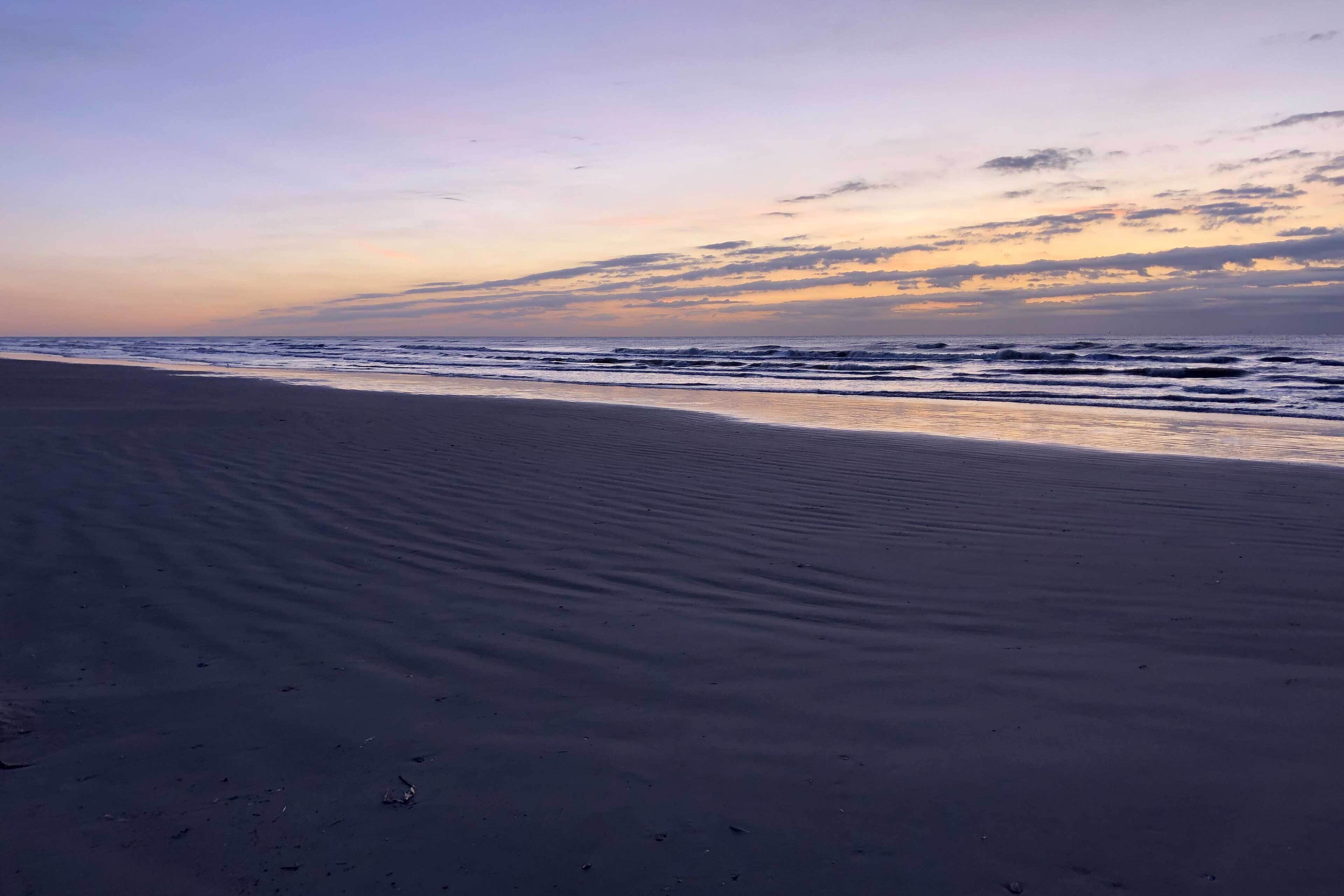 A beach with a wide sandy shore and gentle waves.