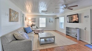 A living room with a gray sofa, a white coffee table, and a television on a white stand.