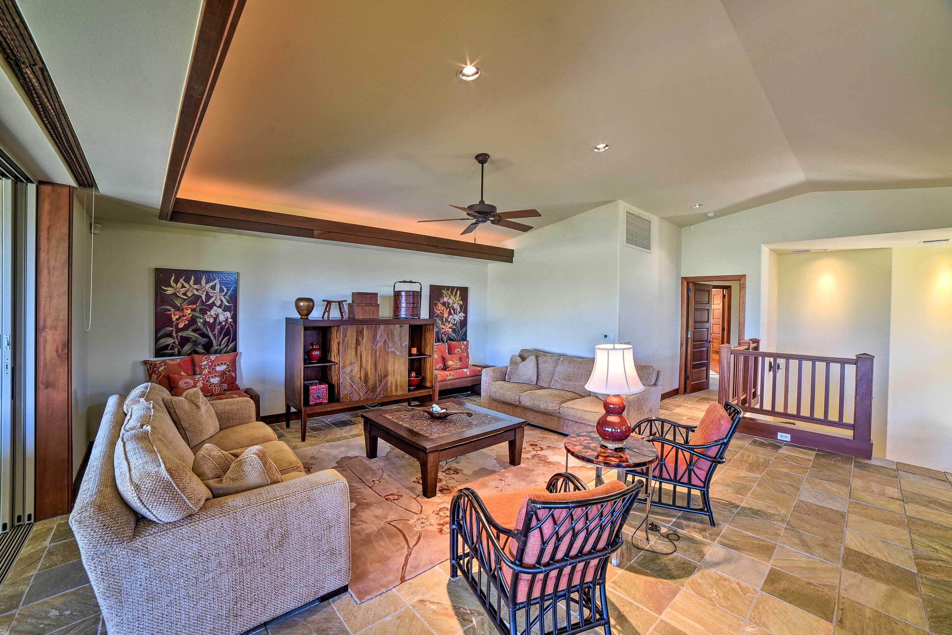 A spacious living room with a sofa, armchairs, a coffee table, and a fireplace. There is a wooden cabinet and a painting on the wall.