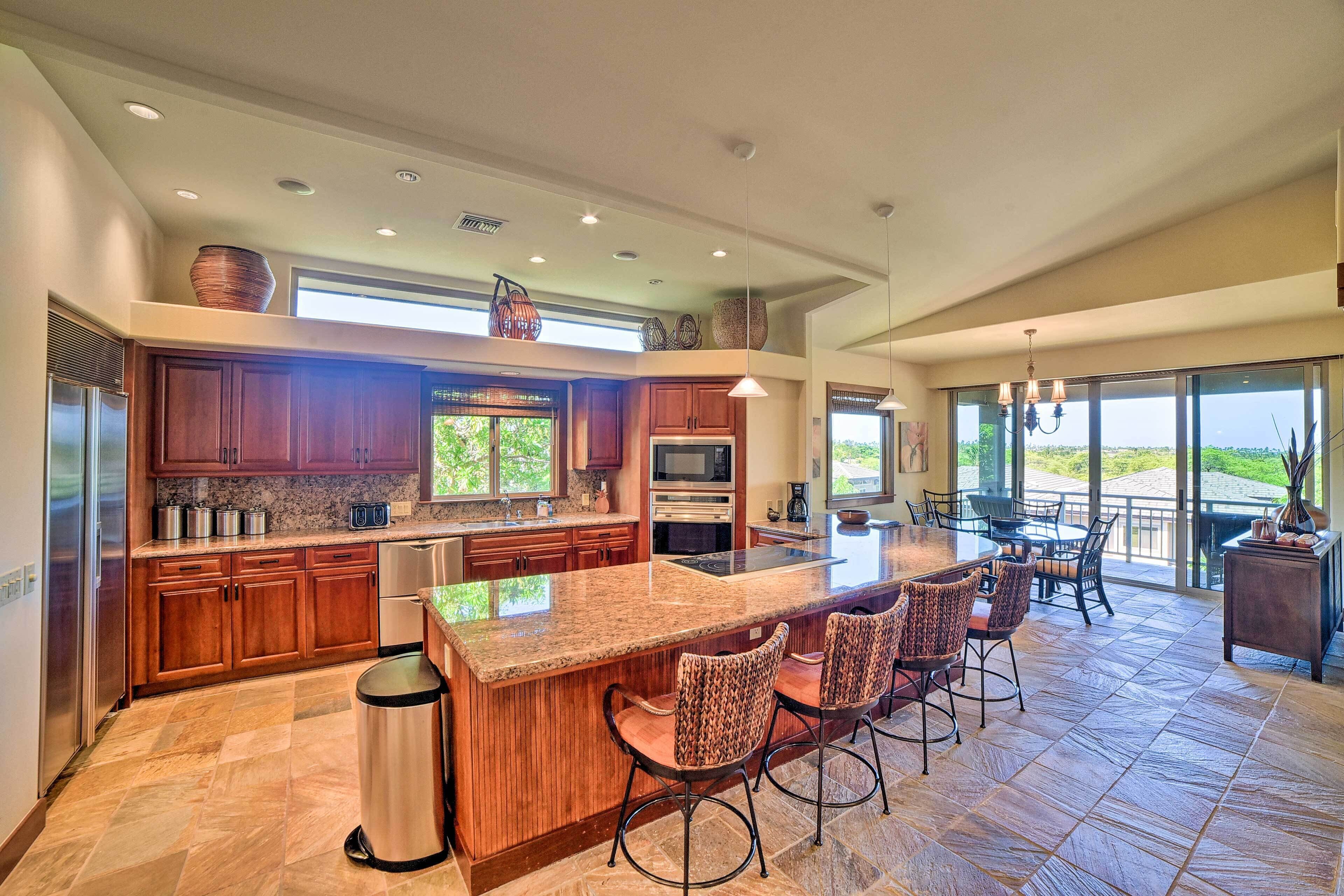 A spacious kitchen with granite countertops, wooden cabinets, and a large island with bar stools.