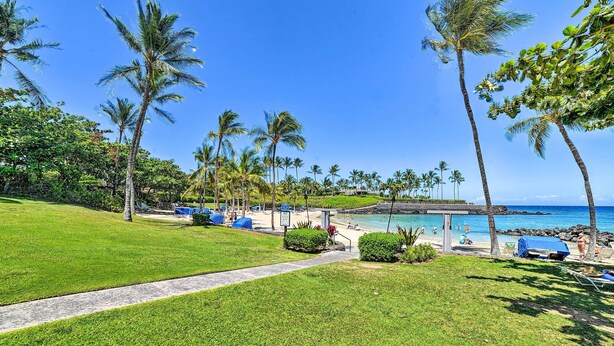 Un resort tropical con vista despejada al océano, palmeras y un camino que lleva a la playa.