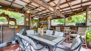 An outdoor patio with a table and chairs, surrounded by wooden walls and a corrugated metal roof.