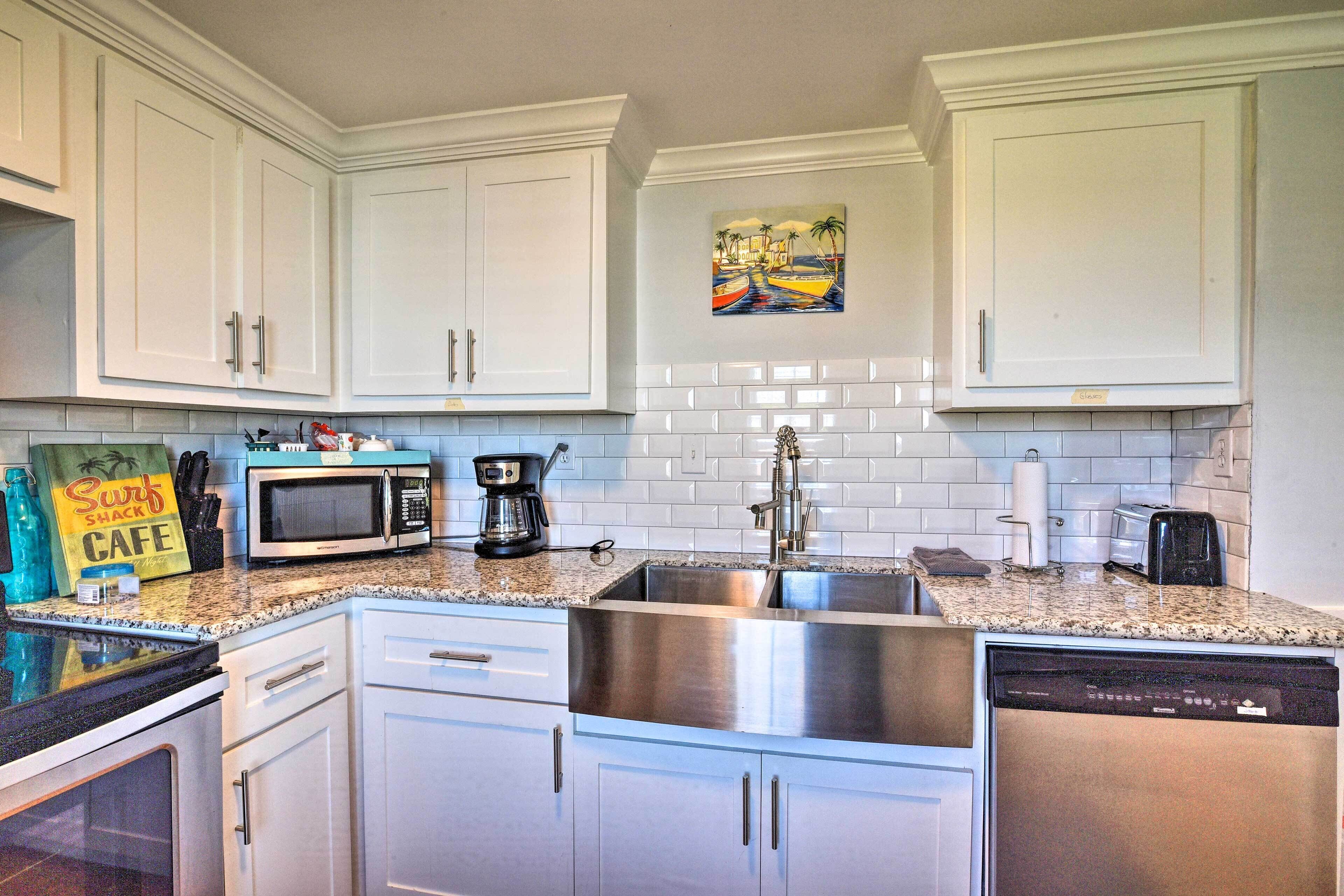 A kitchen with white cabinets, a stainless steel sink, a microwave, a coffee maker, and a dishwasher.