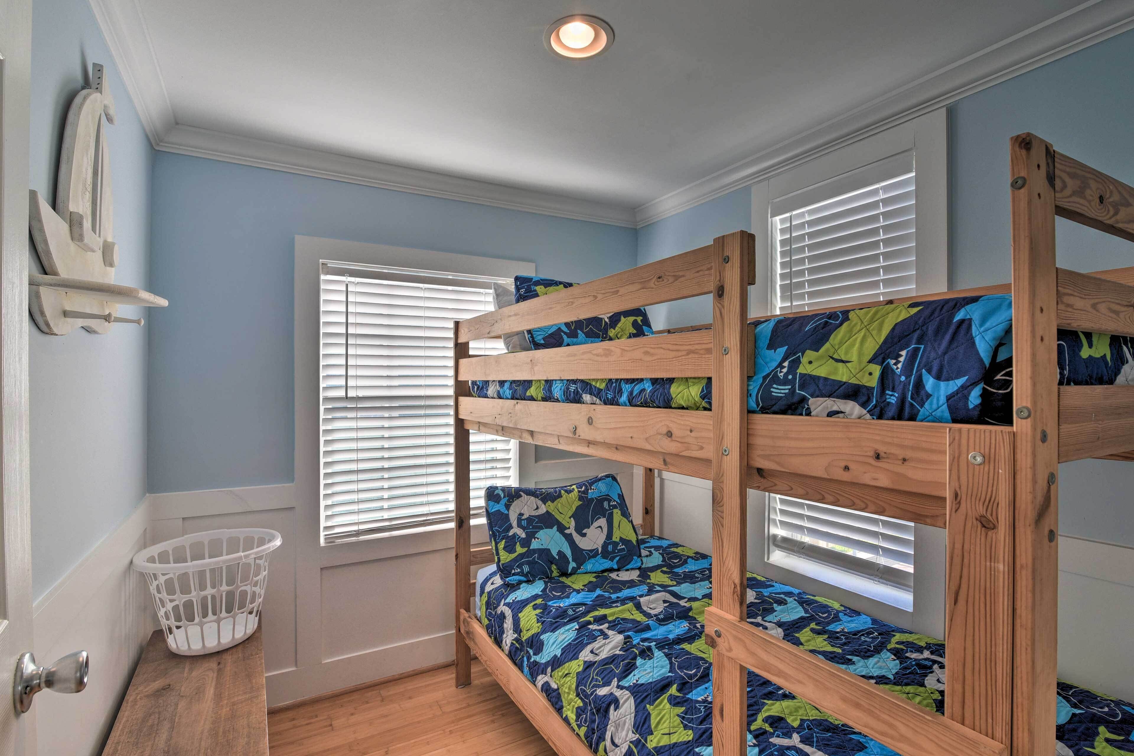 A bunk bed with a patterned bedspread, a white basket, and a wooden shelf.