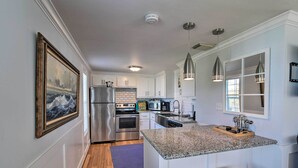 A modern kitchen with white cabinets, stainless steel appliances, a granite countertop, and pendant lighting. - Steps to Beach! 'surf Cottage' in Galveston (Galveston)