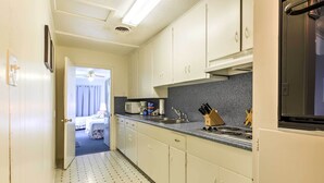 Una cocina estrecha con armarios blancos, un microondas, un fregadero y una estufa.