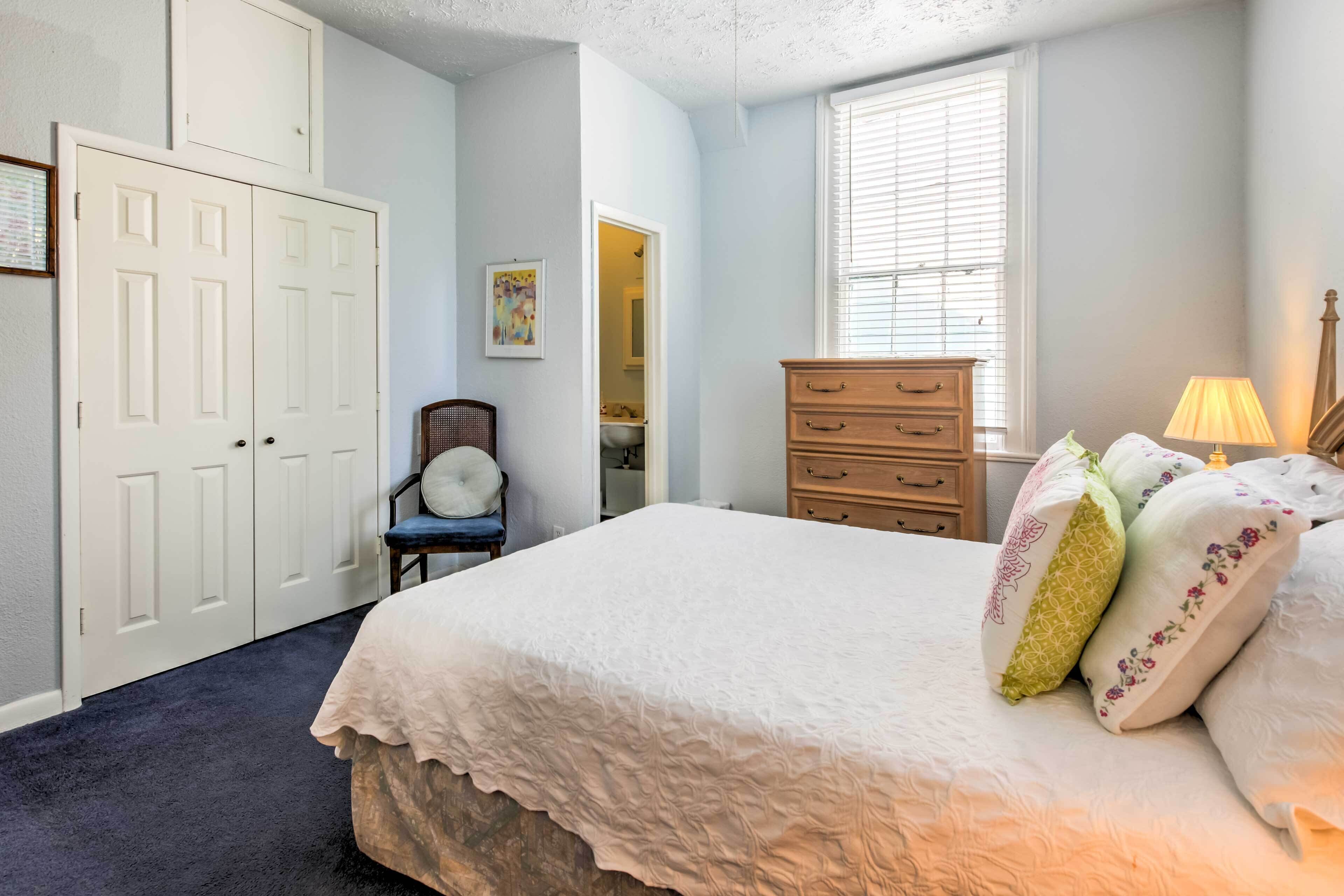 A bedroom with a large bed, a dresser, a chair, and a window.