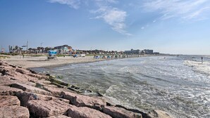 Una playa con costa rocosa, sombrillas y sillas de playa.