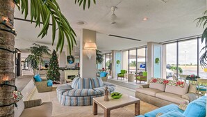 A spacious lobby with a large seating area, a Christmas tree, and large windows offering a view of the outside. - Heated Pool + Gulf View: Galvestonian Resort Condo (Galveston)