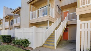A multi-story residential building with a central staircase, white railings, and a gated entrance. - Balcony & Pool Access: Condo in Galveston! (Galveston)