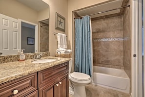 A bathroom with a granite countertop, a white sink, a toilet, and a bathtub. - Walk to Beach: Lavish Resort Escape in Galveston! (Galveston)