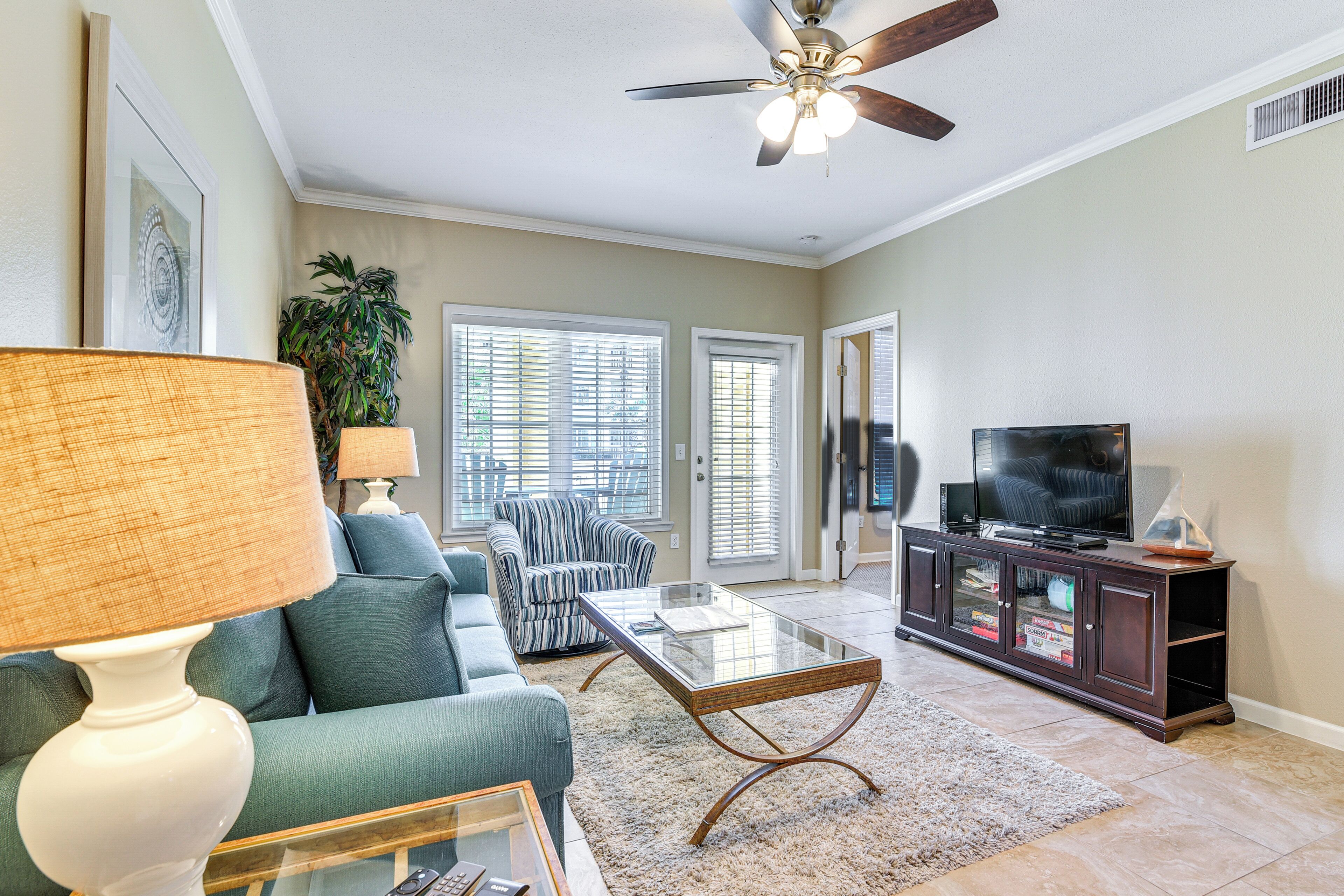 A living room with a sofa, a coffee table, a television, and a ceiling fan.