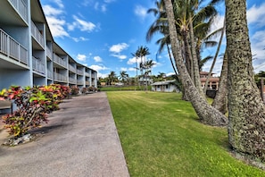 A hotel with a long row of rooms, a grassy lawn, and palm trees. - Condo w/ Lanai at Beginning of Road to Hana! (Paia)