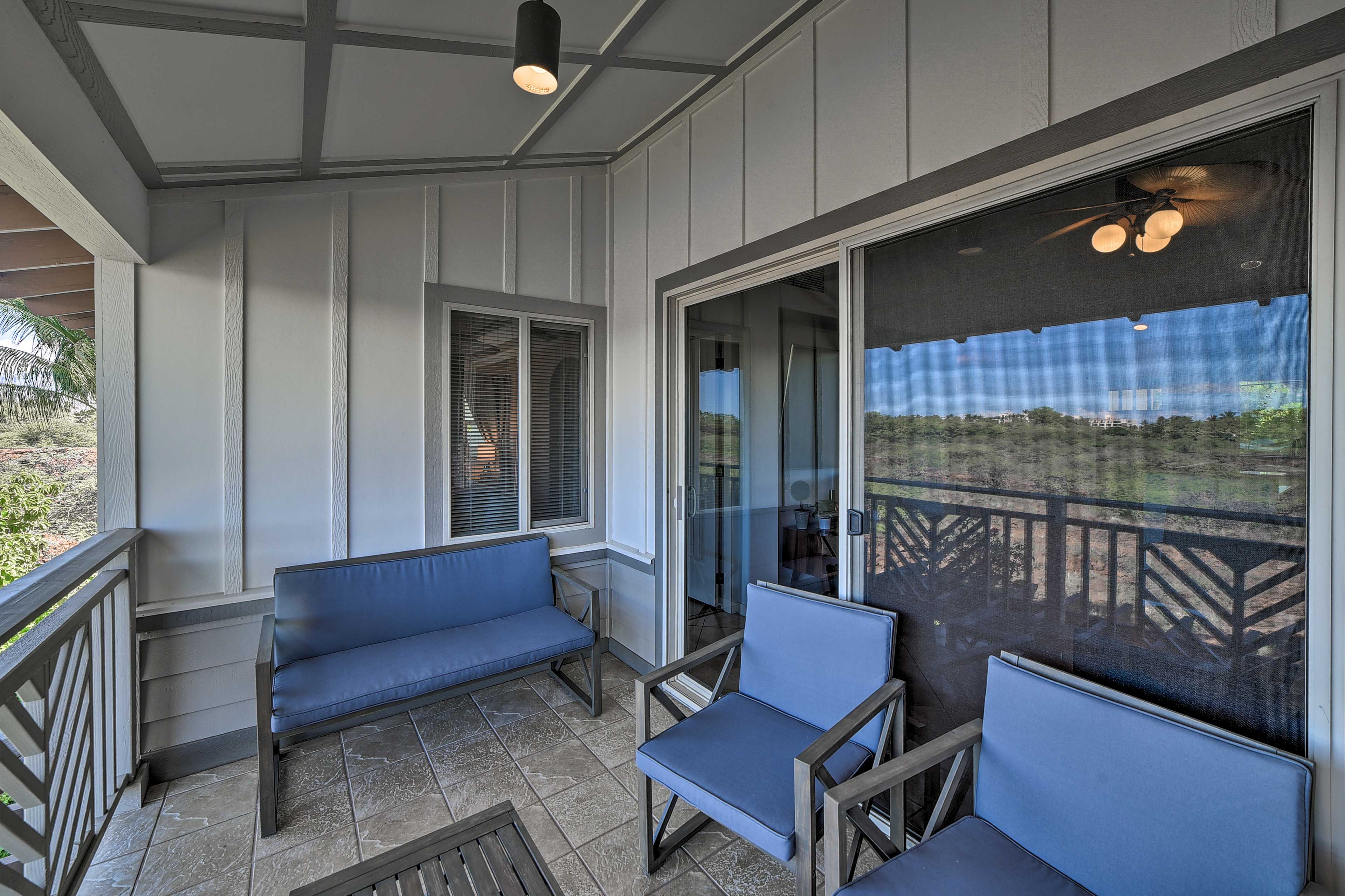 A covered outdoor seating area with a bench and chairs, a glass door leading outside, and a ceiling fan.