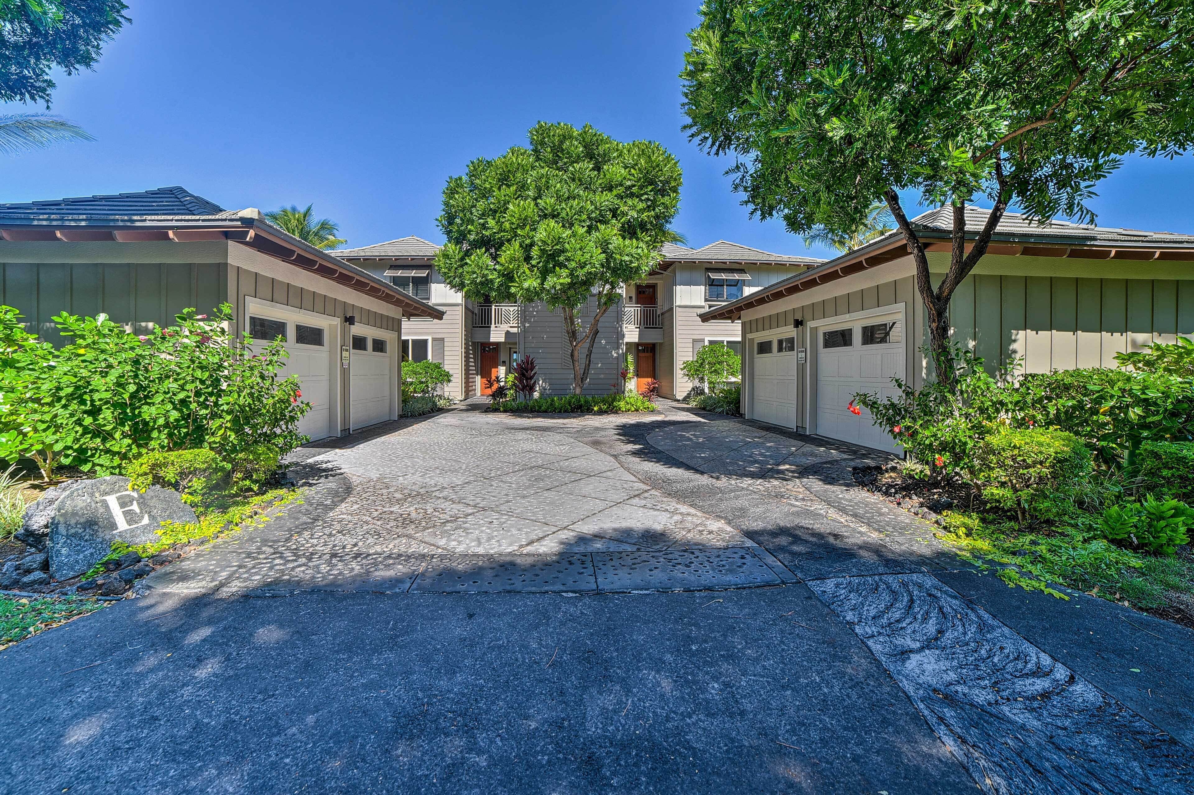 A residential building with a central tree, a paved driveway, and a rock with the letter "E".