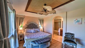 Quarto com uma cama grande, uma cadeira e um ventilador de teto.