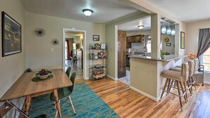 A modern kitchen with a bar area, wooden flooring, and a dining area with a table and chairs. - Vintage Downtown Vegas Retreat < 3 Mi to Strip! (Las Vegas)
