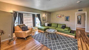 A living room with a green sofa, a tan armchair, a patterned rug, and a floor lamp. - Vintage Downtown Vegas Retreat < 3 Mi to Strip! (Las Vegas)