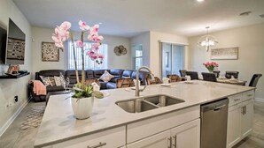 A modern kitchen with a large island, stainless steel appliances, and a dining area with a sofa and chairs.